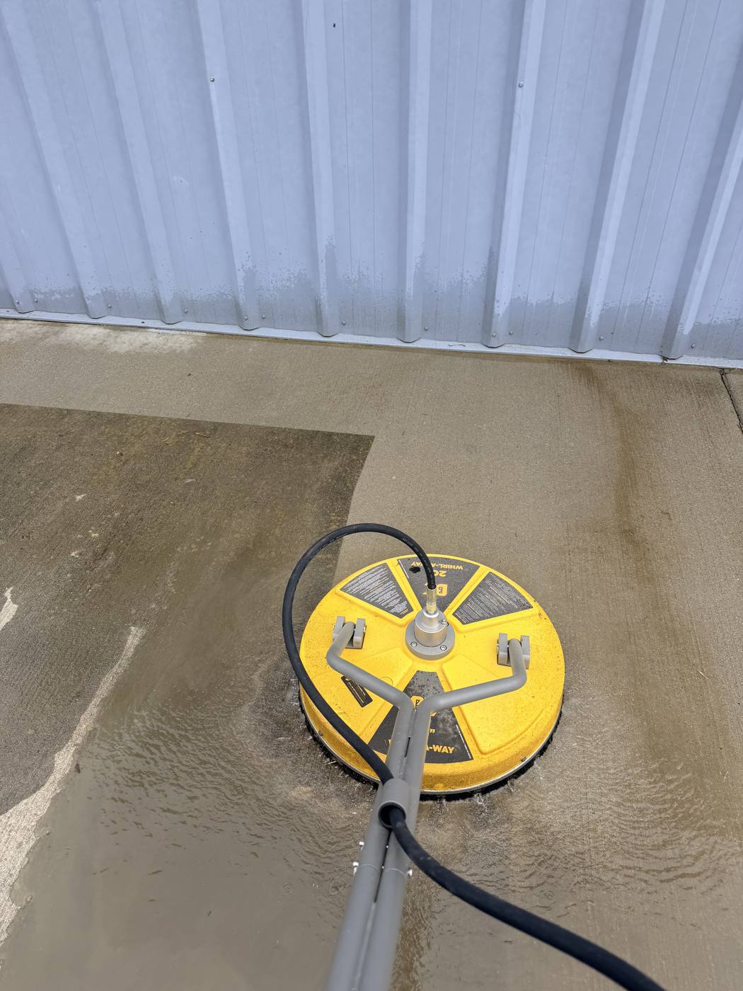Surface cleaner stripping dirt off a concrete driveway