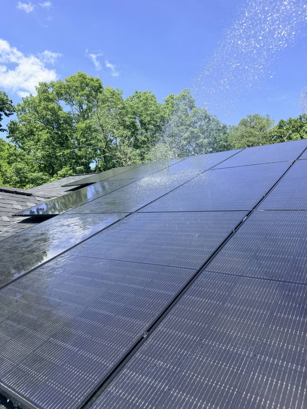 Rinsing water off solar panels during a roof cleaning